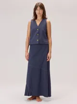 Chaleco negro sin mangas, de corte recto y largo a la cintura, con cuello redondo y cierre frontal oculto.