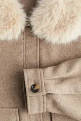 Campera de sarga con acabado cepillado, corte holgado y hombros caídos. Presenta un cuello extraíble de pelo sintético, cierre frontal con botones, bolsillos delanteros con solapa y puños abotonados.