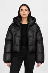 Campera puffer corta de color negro, con acabado brillante, capucha ajustable con cordones, cierre frontal y bolsillos laterales con cierre.