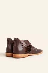 Sandalia de cuero color marrón chocolate, con suela plana y diseño calado con detalles trenzados.