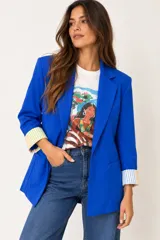 Blazer de corte clásico color azul francia, con solapas tradicionales, bolsillos frontales con solapa y mangas con vuelta que revelan un forro interior a rayas multicolor.