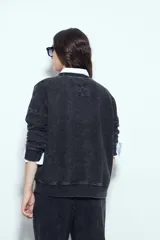 Buzo negro con efecto lavado y costuras verticales a la vista, de calce relajado.