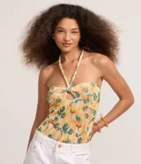 Body femenino con estampado de bananas en tonos amarillo, naranja y verde. Diseño de frente única con lazo anudado en el centro del busto que genera un corte tipo ojal.