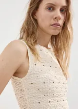 Top sin mangas de tejido texturizado con efecto arrugado y diseño entallado, de cuello redondo y color beige con pequeños detalles brillantes.