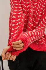 Sweater de punto con diseño de patrón geométrico en colores rojo y blanco, cuello redondo y mangas largas.