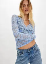 Blusa de encaje transparente color celeste, con escote en V y mangas largas. Presenta un diseño ajustado con textura floral y costuras que realzan la silueta.