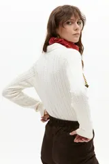 Sweater tipo polo color blanco roto, tejido en ochos, con cuello clásico y media cartera de botones.