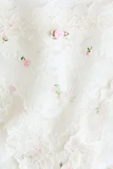 Pack de dos bombachas tipo hipster de encaje blanco, con cintura media, refuerzo forrado y cobertura media en la parte trasera. Una de ellas presenta pequeños bordados de rosas rosadas.