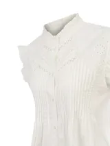 Blusa blanca de algodón orgánico con cuello alto, detalles de bordados y calados decorativos en el canesú, y mangas cortas con volados.
