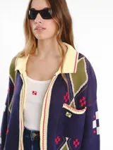 Campera tejida en jacquard con cierre frontal, cuello tipo polo y bolsillos delanteros. Diseño multicolor con estampado geométrico de rombos y detalles bordados a mano.