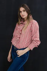 Camisa de algodón con estampado de cuadros en rojo y blanco, con detalles de bordado vertical. Presenta volados románticos en la parte frontal, cuello y puños, con un corte clásico y holgado.
