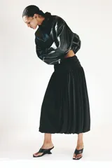 Pollera midi de punto color negro con diseño de bajo globo que crea una silueta abullonada. Cuenta con una cintura ancha elastizada y frunces.