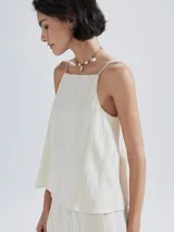 Blusa sin mangas color beige claro, con escote cuadrado y tirantes finos. La tela presenta una textura acanalada vertical.