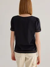 Remera color crema de algodón y lino, con cuello en V y mangas cortas abullonadas. Presenta cartera decorativa de botones en cuerpo y mangas.