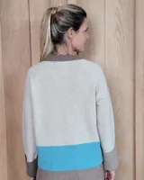 Cardigan de punto color beige, con escote en V, cierre frontal de botones y mangas largas con puños anchos acanalados.