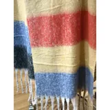 Bufanda rectangular de tejido grueso con diseño de cuadros en tonos azul, naranja, gris y beige, terminada con flecos en los extremos.