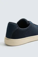 Zapatillas deportivas de hombre color azul marino, con capellada de tejido de rejilla y suela plana color crema.