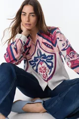 Camisa de lino de manga larga, con cuello y botones frontales. Presenta un estampado artístico y colorido en tonos rosados, azules y blancos, con motivos que recuerdan a escudos o medallones.