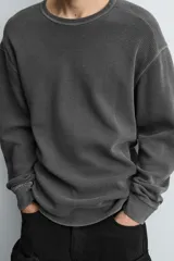Camiseta de manga larga con cuello redondo, confeccionada en tejido de algodón con textura tipo waffle y efecto lavado. Presenta un corte relajado con puños en rib y bajo irregular.
