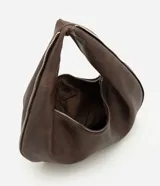 Bolso tipo baguette de formato curvo, confeccionado en poliuretano con acabado que imita el cuero. Presenta una estructura flexible con asa integrada y cierre superior metálico aparente que recorre el contorno.
