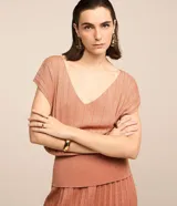 Blusa de manga corta color salmón, confeccionada en viscosa con escote en pico e hilos metalizados con textura efecto plisado. Tiene un diseño más ajustado en la cintura.