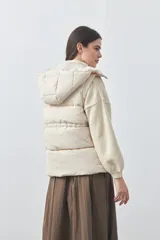 Chaleco puffer negro con diseño acolchado, capucha desmontable y cierre frontal. Cuenta con cordones ajustables en la cintura y bolsillos laterales.