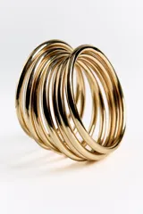 Pack de pulseras rígidas doradas, compuestas por múltiples aros delgados superpuestos, creando un efecto de brazalete ancho y texturizado.