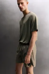 Short deportivo de entrenamiento color marrón, confeccionado en tejido técnico ligero y elástico. Cuenta con cintura elástica ajustable con cordón, bolsillos frontales, bolsillo trasero con cierre y aberturas laterales en el bajo. Incluye detalle de logo estampado en la pernera.