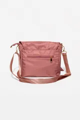 Cartera bandolera de tela color rosa, con múltiples bolsillos frontales, cierre principal y correa ajustable al tono.