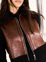 Chaleco marrón con cierre frontal, paneles de cuero en el frente y espalda de tejido de punto negro.