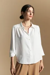 Camisa de manga larga con caída fluida, diseño de silueta suelta, cuello clásico y cierre frontal con botones.