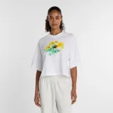 Remera blanca de corte cuadrado y holgado, con cuello redondo y mangas cortas. Presenta un estampado frontal con diseño de flores en estilo acuarela y el logo de la marca en el centro.