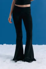 Pantalón tipo oxford de tiro medio, confeccionado en lycra con textura similar al neoprene. Presenta un corte ajustado en la parte superior que se ensancha hacia el ruedo, con tajos laterales en la botamanga y logo bordado en el frente.