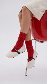 Chatita estilo bailarina confeccionada en pelo sintético color blanco, con tira de cuero sintético negra y hebilla metálica ajustable en el empeine.