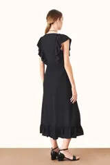 Vestido midi negro con escote en V y volados en los hombros y el ruedo. Presenta un ajuste fruncido en la cintura con lazos ajustables.