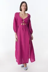 Vestido midi fucsia de lino, con escote en V, mangas largas abullonadas, lazos frontales y tajo lateral.