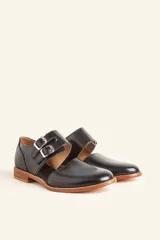 Zapato tipo oxford abierto en los laterales, confeccionado en cuero vacuno negro. Presenta doble tira con hebillas metálicas en el empeine y detalle de tachas plateadas en el contorno del talón y la puntera.