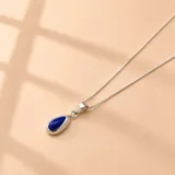 Collar de cadena fina de plata 925 con dije en forma de gota que contiene una piedra de resina azul intenso engastada en metal plateado.