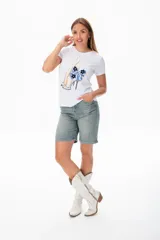 Remera blanca de algodón con estampado de piernas con zapatos de tacón y moño azul.