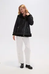 Campera de estilo aviador confeccionada en eco-cuero negro con interior de piel sintética oscura. Presenta cierre frontal cruzado, solapas amplias, bolsillos laterales con cierre y detalles de hebillas ajustables en los puños.