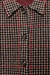 Abrigo de corte recto confeccionado en 100% lana, con estampado de pata de gallo en tonos tierra, negro y detalles en rojo. Presenta cuello solapa, cierre frontal con botones y bolsillos delanteros de vivo.