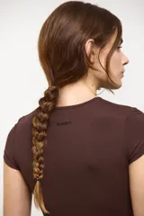 Remera tipo baby tee color marrón espresso, de corte ajustado al cuerpo, con escote redondo y mangas cortas. Confeccionada en tejido ultra liviano y suave con compresión media.