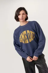 Sweatshirt azul marino jaspeado con cuello redondo y hombros caídos. Presenta un gráfico desgastado en color amarillo con el texto "GAME DAY" en forma ovalada.