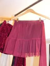 Pollera corta de tiro medio-bajo, color bordó, con volado en el ruedo y cinto integrado con detalle de lentejuelas.
