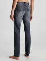 Pantalón de jean gris oscuro de corte slim, con cintura media, cinco bolsillos y cierre con cremallera.