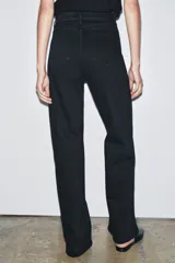 Jeans de tiro alto con corte wide leg y largo completo. Presenta diseño de cinco bolsillos, trabillas en la cintura y cierre frontal con cremallera y botón, con un acabado de efecto lavado.