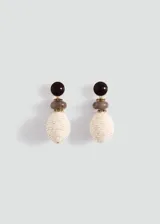Aros colgantes de diseño estructurado que combinan una cuenta superior redonda y oscura, una cuenta intermedia grisácea y una cuenta inferior ovalada revestida en rafia natural de tono claro, unidas por detalles metálicos dorados.