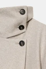 Abrigo corto de paño en color negro, con cuello subido, cierre frontal cruzado con botones, mangas largas con trabillas en los puños y bolsillos delanteros de vivo.