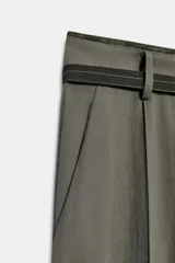 Pantalón de tiro alto con corte ancho y pernera recta. Presenta raya planchada en el delantero, bolsillos laterales y cierre frontal con cremallera y ganchos metálicos. Incluye un cinturón fino en tejido a contraste.