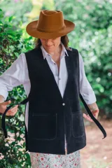 Chaleco largo de gamuza negra con bolsillos frontales aplicados, escote en V y tiras laterales para atar.